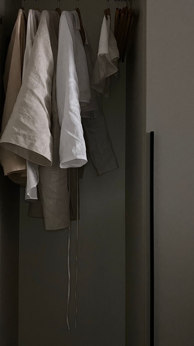Neutral linen garments hanging together on wooden hangers